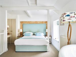 a bedroom with a large bed with a blue headboard at Lugger Hotel ‘A Bespoke Hotel’ in Portloe