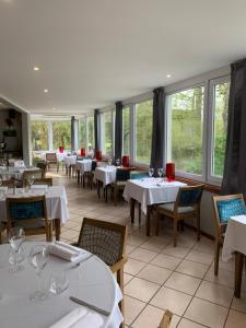 a restaurant with white tables and chairs and windows at Le Clos De Mutigny in La Chaussée-sur-Marne