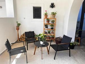 a room with three chairs and a table and a shelf with plants at Paprika vendégház in Harkány