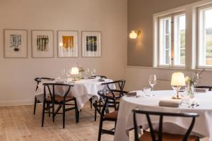 a dining room with tables and chairs with white tablecloths at Molskroen in Ebeltoft
