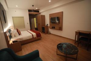 a bedroom with a bed and a desk and a television at Celestial International in Taliparamba