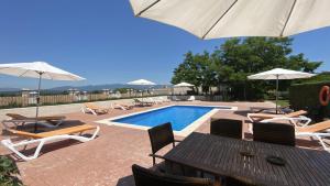 a pool with chairs and a table and umbrellas at Can Genis Turismo Rural in Peralada