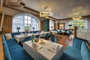 a restaurant with white tables and blue chairs at Schlosshotel Grünwald in Grünwald