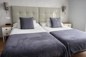 a bedroom with two beds with blue pillows at Hotel Villa del Son in Porto do Son