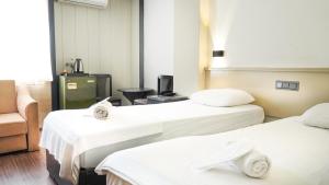 a room with two beds and a chair at Hotel Güleryüz 2 in Antalya