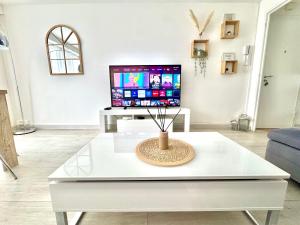 a living room with a tv and a white coffee table at Appartement Chilly Mazarin T3 Proche Aéroport Orly in Chilly-Mazarin
