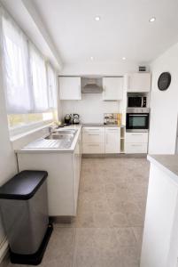 a white kitchen with white cabinets and a sink at Appartement Chilly Mazarin T3 Proche Aéroport Orly in Chilly-Mazarin