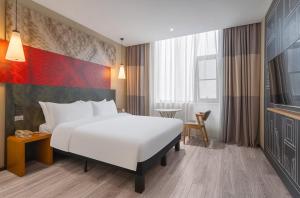 a hotel room with a large bed and a table at Ibis Chengdu Wuhouci Jinli in Chengdu +13 photos