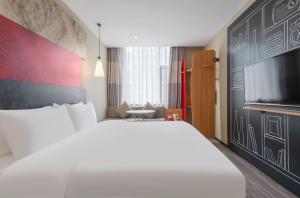 a bedroom with a large white bed and a tv at Ibis Chengdu Wuhouci Jinli in Chengdu
