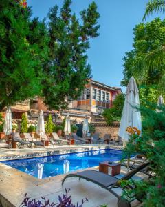 a swimming pool with white umbrellas and chairs at Tuvana Hotel in Antalya