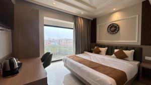 a bedroom with a bed with a clock on the wall at Hotel Vivaan - Walk to Banke Bihari Temple in Vrindāvan