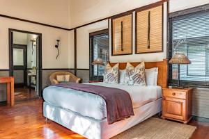 a bedroom with a bed and a table and windows at Umthiba Bush Lodge in KwaNibela
