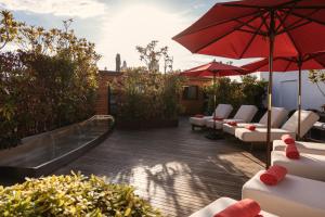 a patio with white couches and red umbrellas at The Principal Madrid, Small Luxury Hotels in Madrid