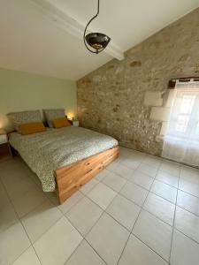 a bedroom with a bed and a stone wall at Gîte à la campagne in Meursac