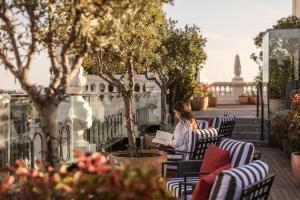 a woman sitting in chairs on a balcony with a laptop at The Principal Madrid, Small Luxury Hotels in Madrid