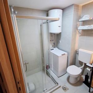 a small bathroom with a toilet and a shower at Luxury Apartment-Aurora 33 Free Parking City Center in Podgorica +35 photos