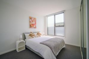 a white bedroom with a bed and a window at Waverley Gardens Modern 3BR Home - Pet Friendly & Parking in Mulgrave