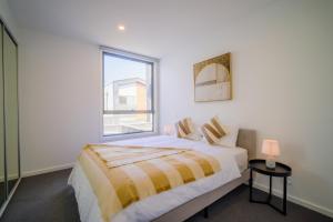 a white bedroom with a bed and a window at Waverley Gardens Modern 3BR Home - Pet Friendly & Parking in Mulgrave