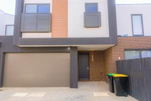 a building with two garage doors and a trash can at Waverley Gardens Modern 3BR Home - Pet Friendly & Parking in Mulgrave