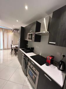 a kitchen with black cabinets and a stove top oven at The Lennox D-Plus Apartments in Accra