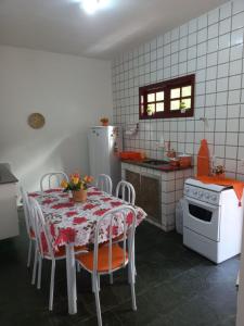 a kitchen with a table with chairs and a refrigerator at Casa Completa na Praia in Saquarema