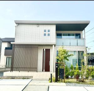 a white house with a brown door at Akikawa Koshi 2 プレミアム鉄骨 一棟貸切ヴィラ in Yuge