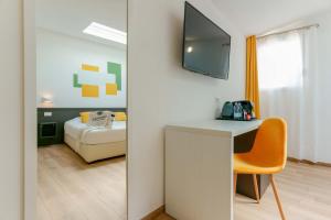 a room with a desk with a television and a bed at Admayora Guest House in Villasimius