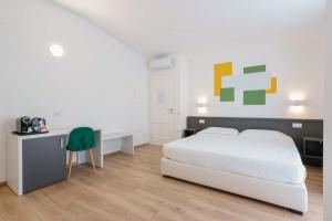 a bedroom with a bed and a desk with a green chair at Admayora Guest House in Villasimius