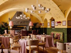 a dining room with tables and chairs and a chandelier at Kulm Hotel St. Moritz in St. Moritz