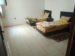 a room with three beds and a tiled floor at اقامة الشام in Laayoune