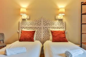 two beds in a hotel room with red pillows at Welcome to Villa Floréal Your tranquil retreat with spa in Saint-Gilles-Croix-de-Vie