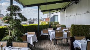 ein Restaurant mit Tischen und Stühlen auf einer Terrasse in der Unterkunft Hyllit Hotel in Antwerpen