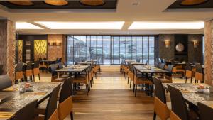 ein Restaurant mit Tischen und Stühlen und großen Fenstern in der Unterkunft Hyllit Hotel in Antwerpen