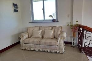 a couch in a living room with a window at Seven Waves Beachfront Residence - La Union in Bagbag Oeste