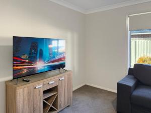 a living room with a flat screen tv on a wooden entertainment center at St Pauls Home in North Wagga