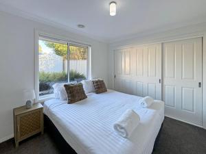 a bedroom with a large white bed with a window at St Pauls Home in North Wagga +29 photos