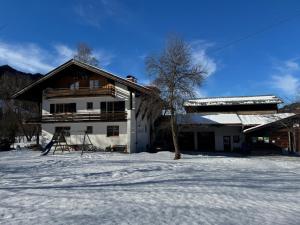 a white house with a tree in the snow at Heulandhof in Bad Hindelang +10 photos
