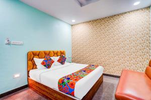 a bedroom with a bed and a chair in it at Via Emara Inn - Lalbagh Botanical Garden in Bangalore