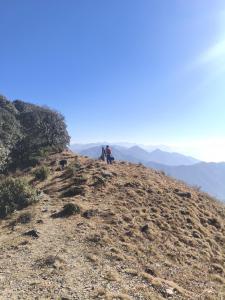 two people sitting on the side of a mountain at Himalayan Cloud Door Camps in Dehradun