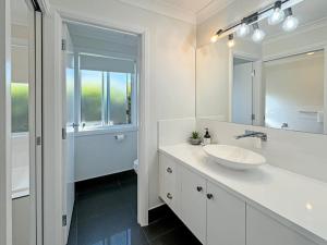 a white bathroom with a sink and a mirror at Paradise Stay in North Wagga +32 photos