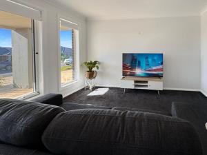 a living room with a couch and a flat screen tv at Paradise Stay in North Wagga