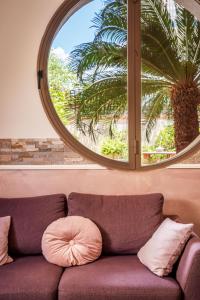 a couch in front of a window with a palm tree at Hotel Alexander in Giardini Naxos