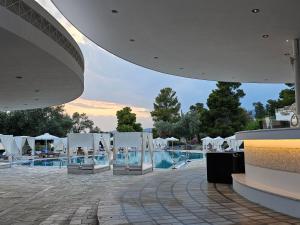 a group of white chairs next to a swimming pool at Paradise Resort Evia, a member of Radisson Individuals in Eretria