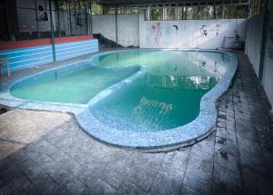 a swimming pool with green water in a building at Edakkal Pool Villa in Ambalavayal