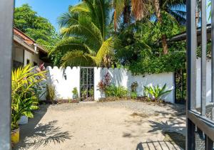 a garden with a white fence and palm trees at Dragonfly Cottage - Courtyard Garden 3 Bedrooms in Bagamoyo