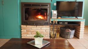 a fireplace in a living room with a television and a table at Lera de cal roger in Verdú