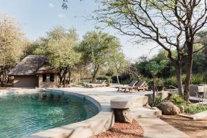 a swimming pool with a picnic table and benches around it at Timbila Game Lodge - Welcome to Land of Leopards and Buffalo in Phalaborwa