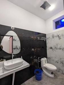 a bathroom with a sink and a toilet and a mirror at Om Coast Gokarna in Gokarna