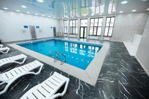 a large swimming pool with two white chairs in a building at Samal Resort and SPA in Taraz