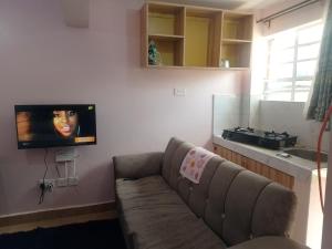 a living room with a couch and a tv on the wall at Masqani studios muthiga in Rungiri